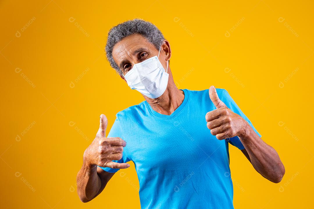 Homem idoso usando mascara branca em fundo amarelo