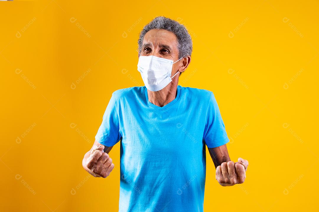Homem idoso usando mascara branca em fundo amarelo