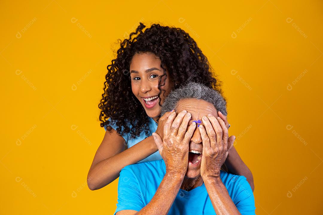 Pai e filha abraçados com camisetas azuis em fundo amarelo