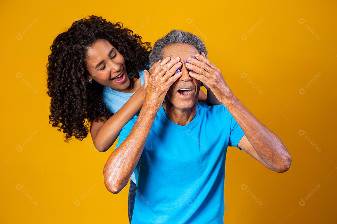 Pai e filha abraçados com camisetas azuis em fundo amarelo