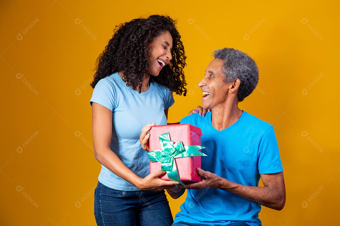 Filha Dando caixa de presente para o pai em fundo amarelo