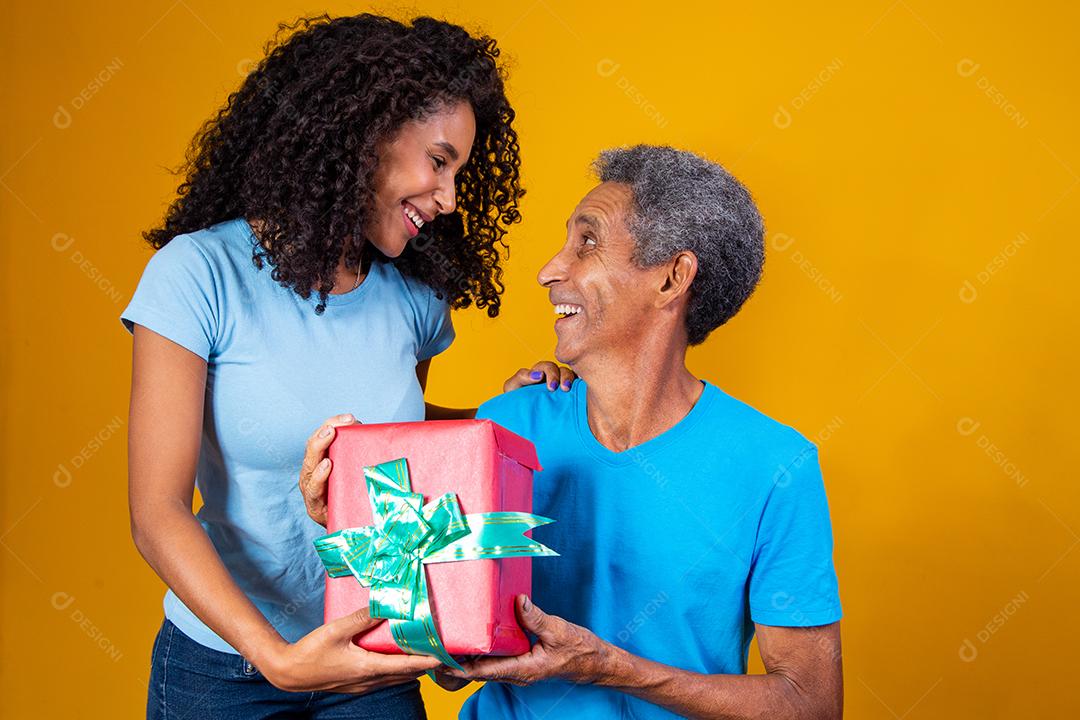 Daughter Giving Gift Box To Father On Yellow Background