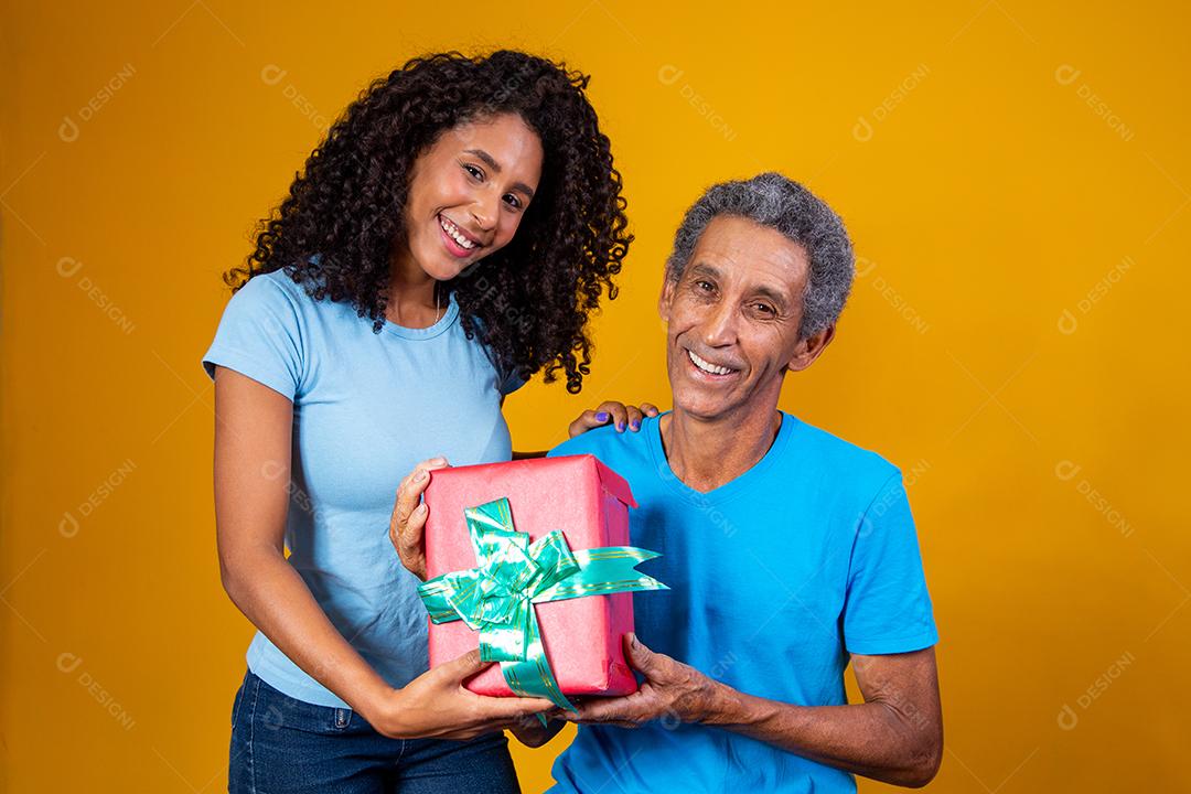 Filha Dando caixa de presente para o pai em fundo amarelo