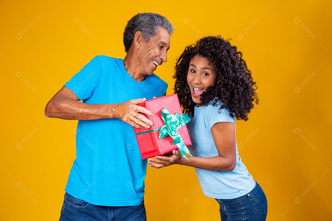 Filha Dando caixa de presente para o pai em fundo amarelo