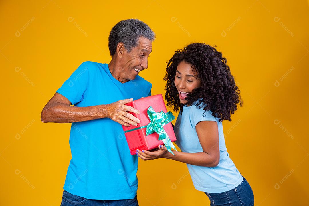 Filha Dando caixa de presente para o pai em fundo amarelo