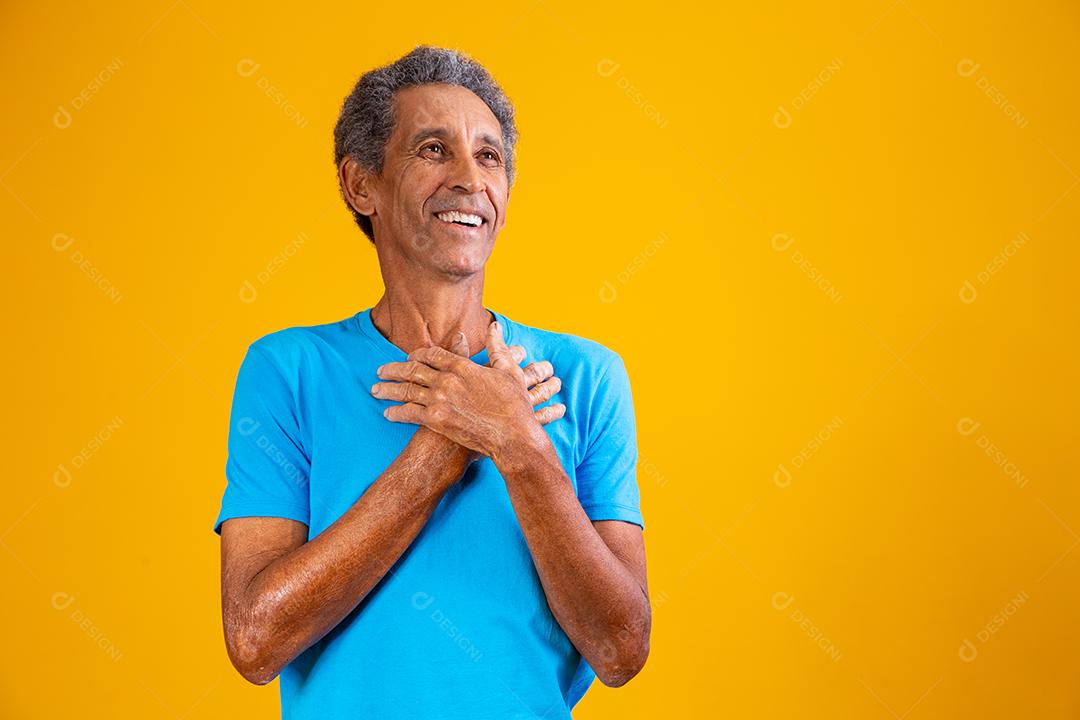 homem afro idoso com a mão no peito com gratidão