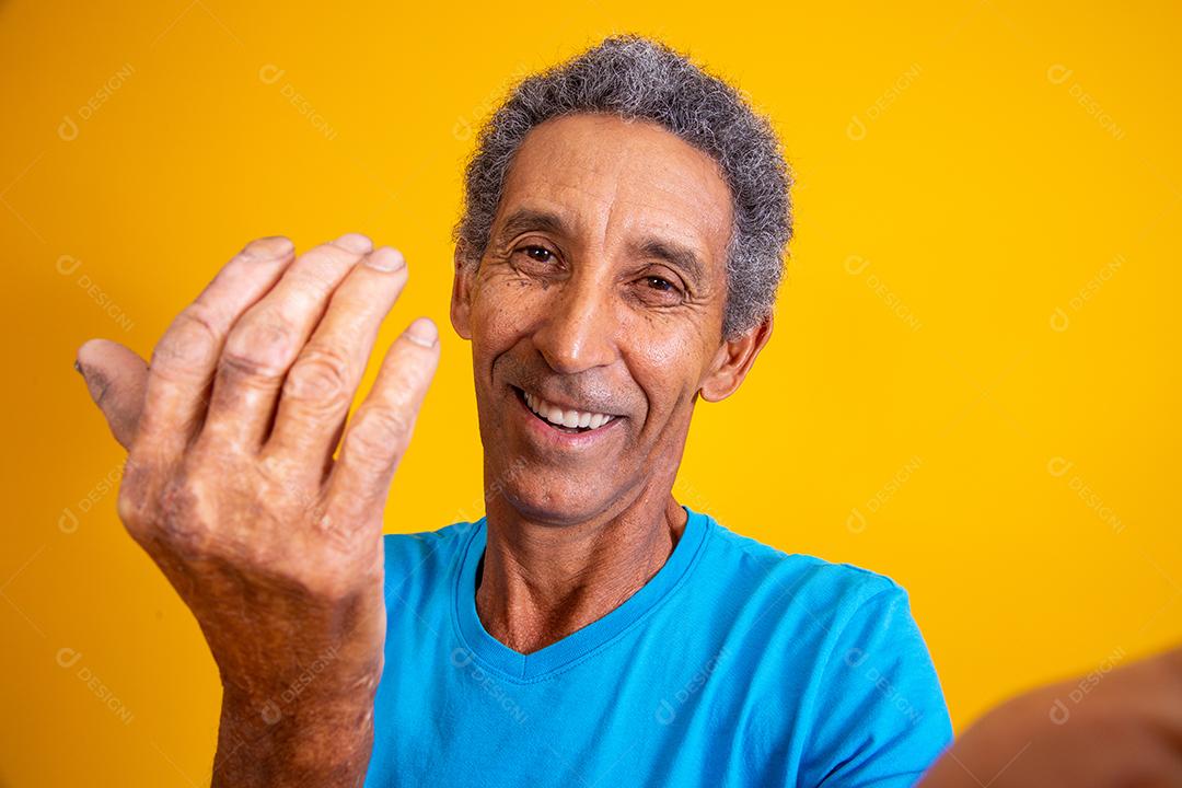 homem idoso fazendo selfie e chamando com a mão venha aqui