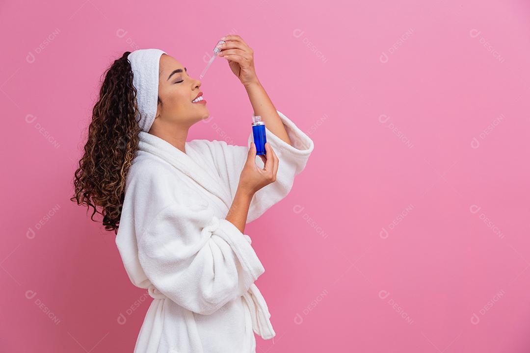Linda jovem afro com óleo cosmético na cor de fundo