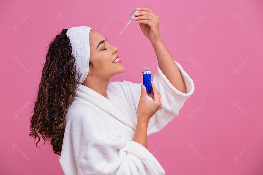 Linda jovem afro com óleo cosmético na cor de fundo