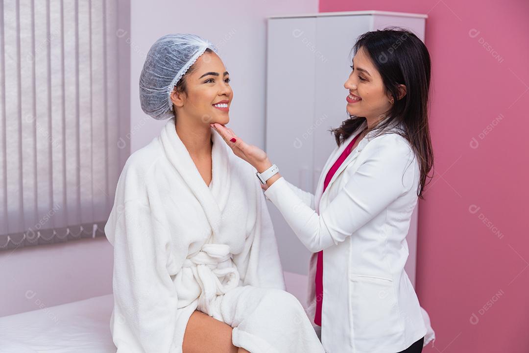 médico ou dentista avaliando o rosto de uma linda mulher afro para tratamento estético