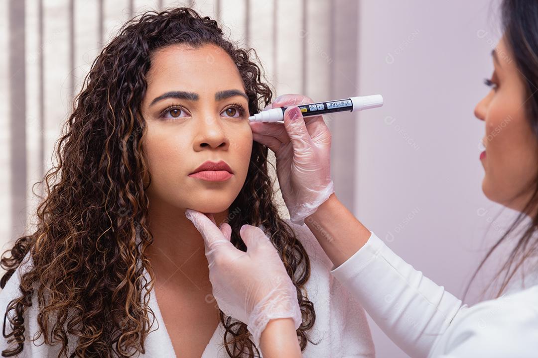 Conceito de cirurgia plástica facial. Fazendo marcação facial para iniciar procedimento estético. Mulher na clínica de beleza