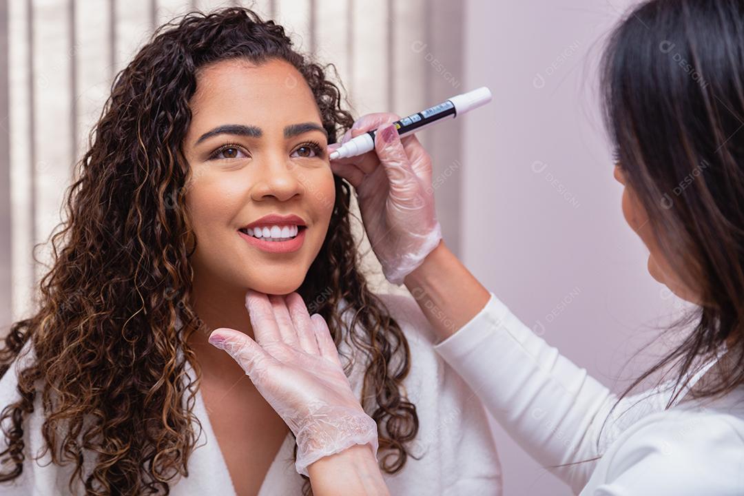 Conceito de cirurgia plástica facial. Fazendo marcação facial para iniciar procedimento estético. Mulher na clínica de beleza