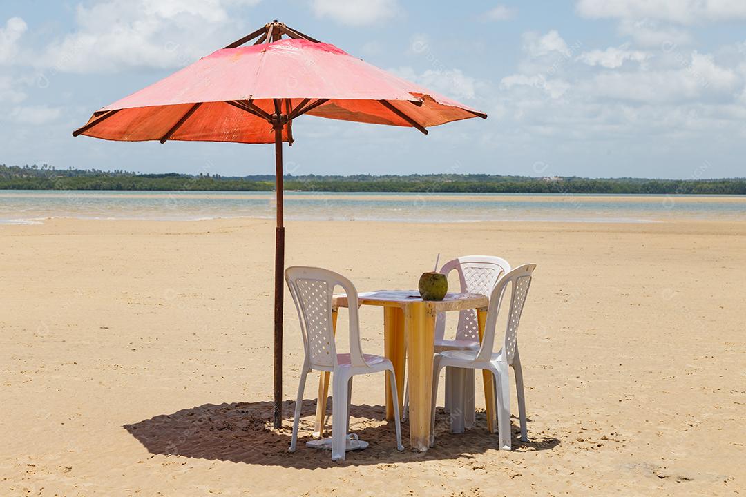 foto de cadeiras e guarda-chuva com um lago ao fundo. Praia, férias e verão