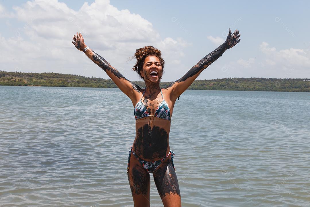 Jovem afro tomando banho em argila natural no rio.
