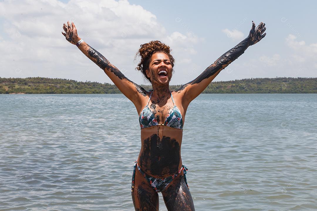 Jovem afro tomando banho em argila natural no rio.
