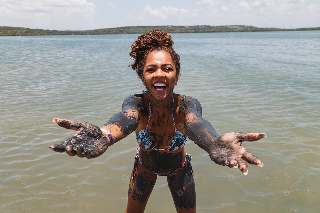Jovem afro tomando banho em argila natural no rio.