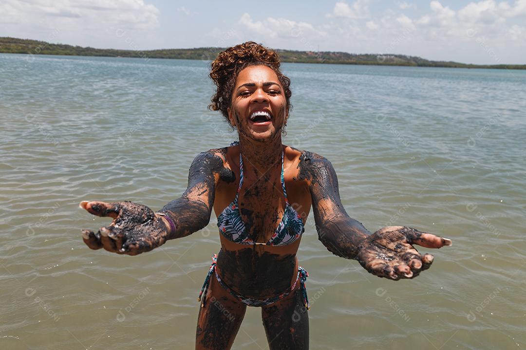 Jovem afro tomando banho em argila natural no rio.