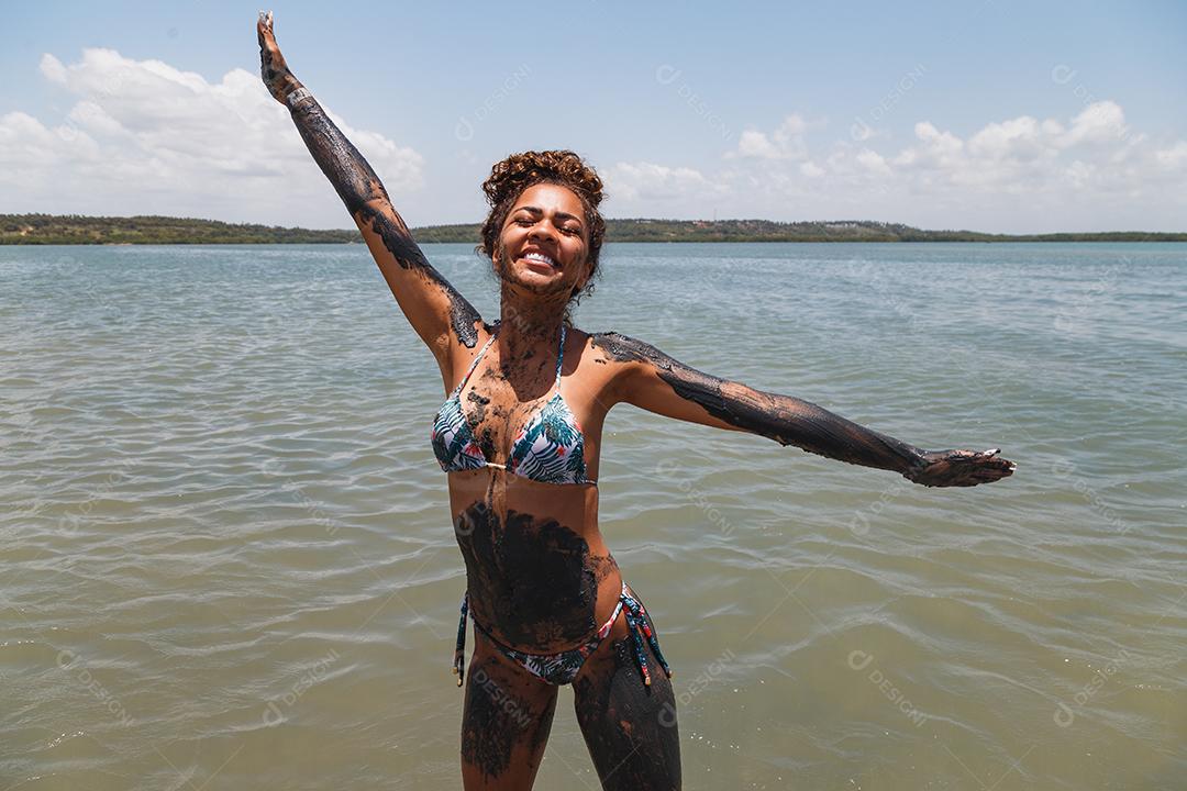 Jovem afro tomando banho em argila natural no rio.