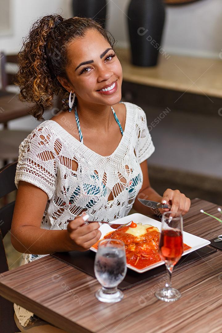 mulher comendo um delicioso prato de carne e macarrão à parmegiana.