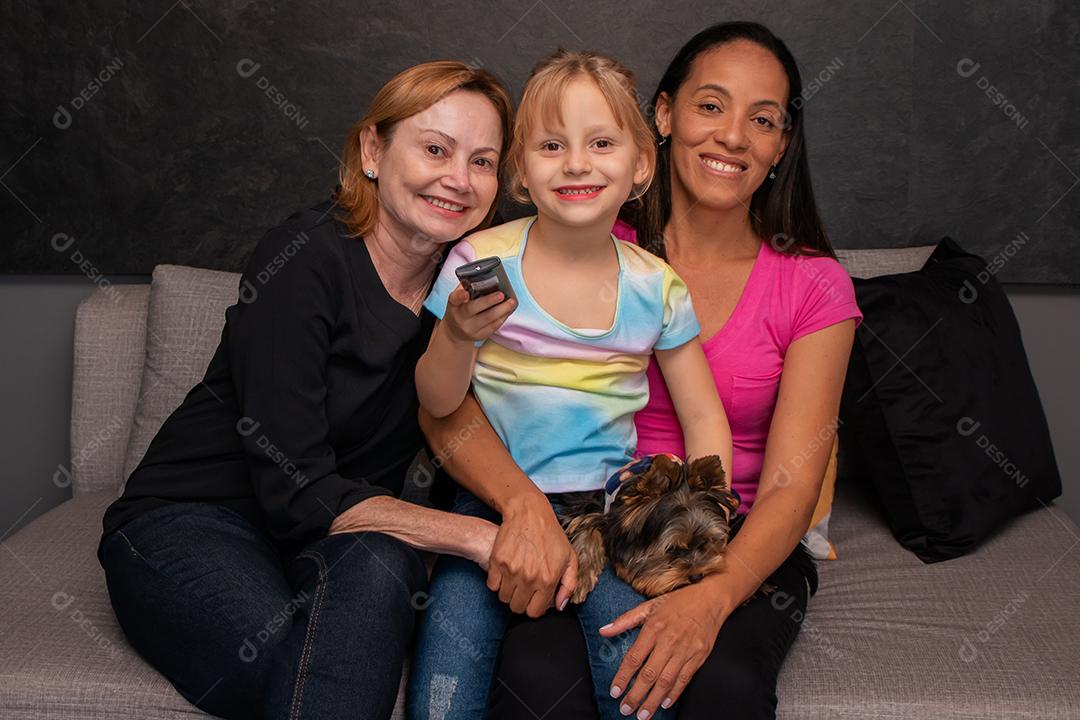 família lésbica e sua filha sentada no sofá com seu cachorro