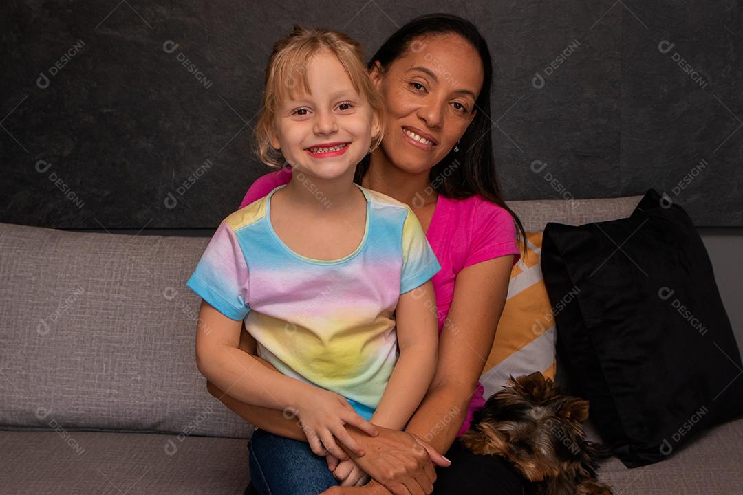 mãe e filha no sofá da sala segurando cada uma cachorrinha