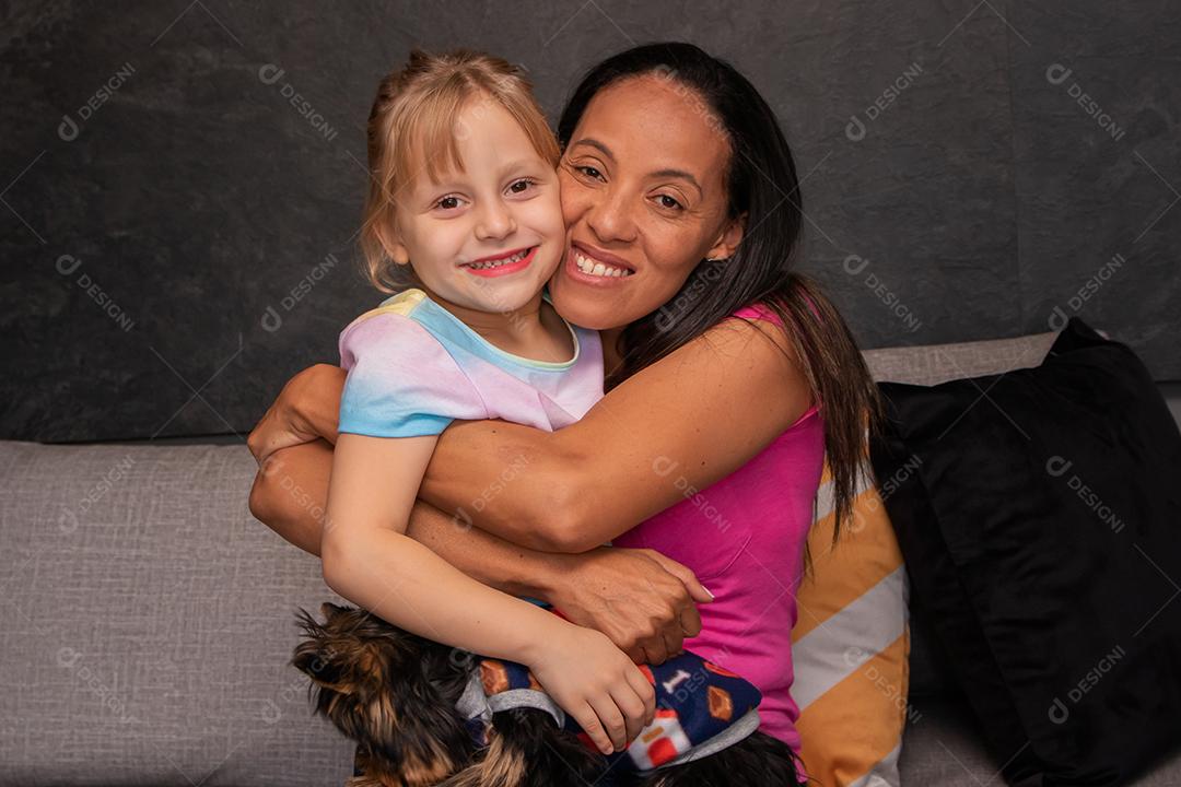 mãe e filha no sofá da sala segurando cada uma