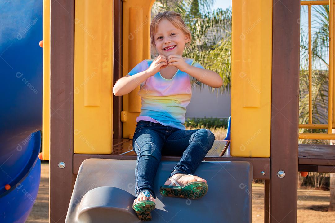 menina sentada no parque. criança brincando no playground