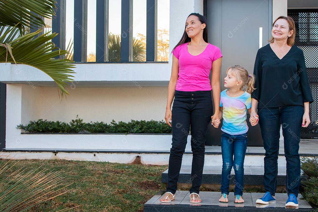casal de lésbicas segurando a mão da filha adotiva na porta de casa. Lesb