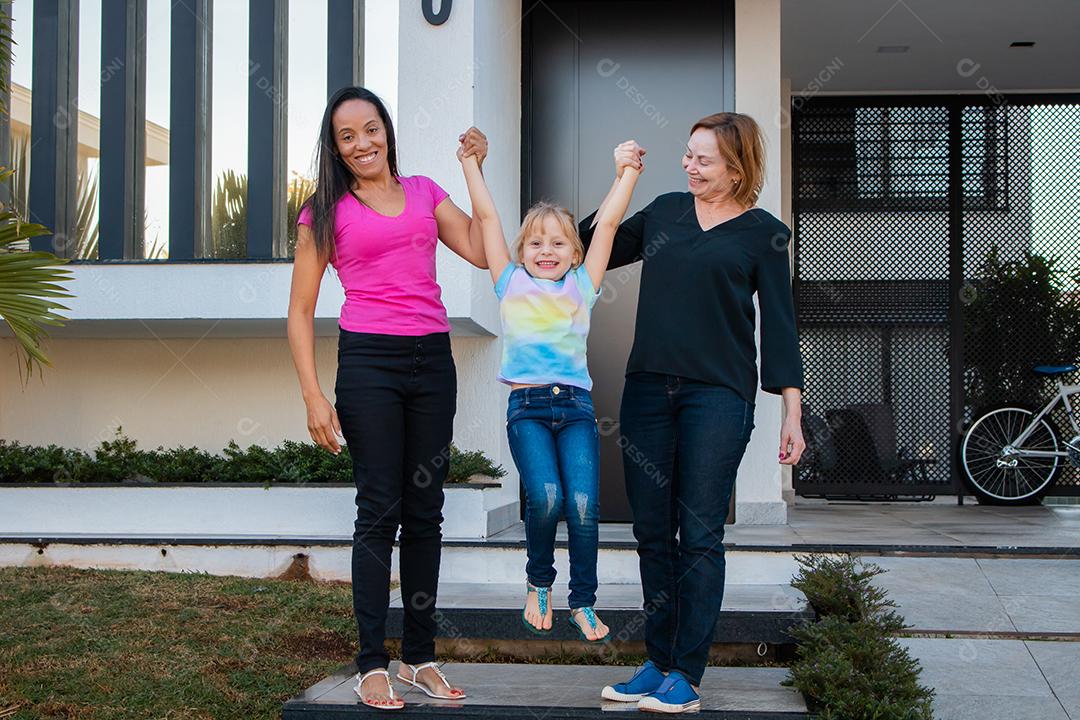 casal de lésbicas segurando a mão da filha adotiva na porta de casa. Lesb