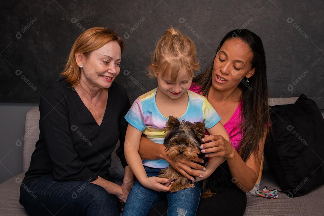 família lésbica e sua filha sentada no sofá com seu cachorro