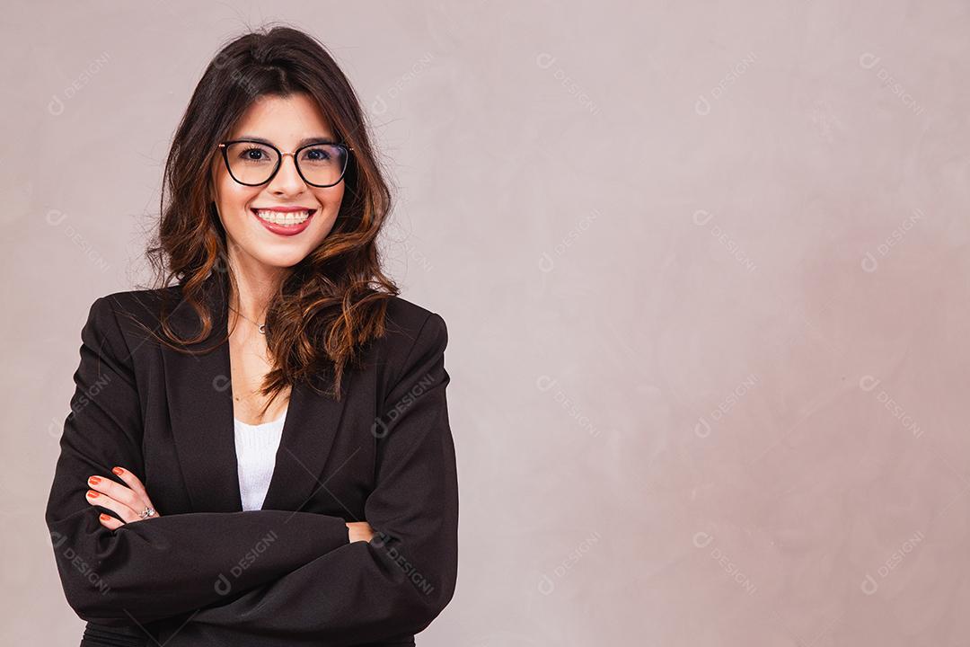 Mulher morena sorridente com óculos posando com os braços cruzados