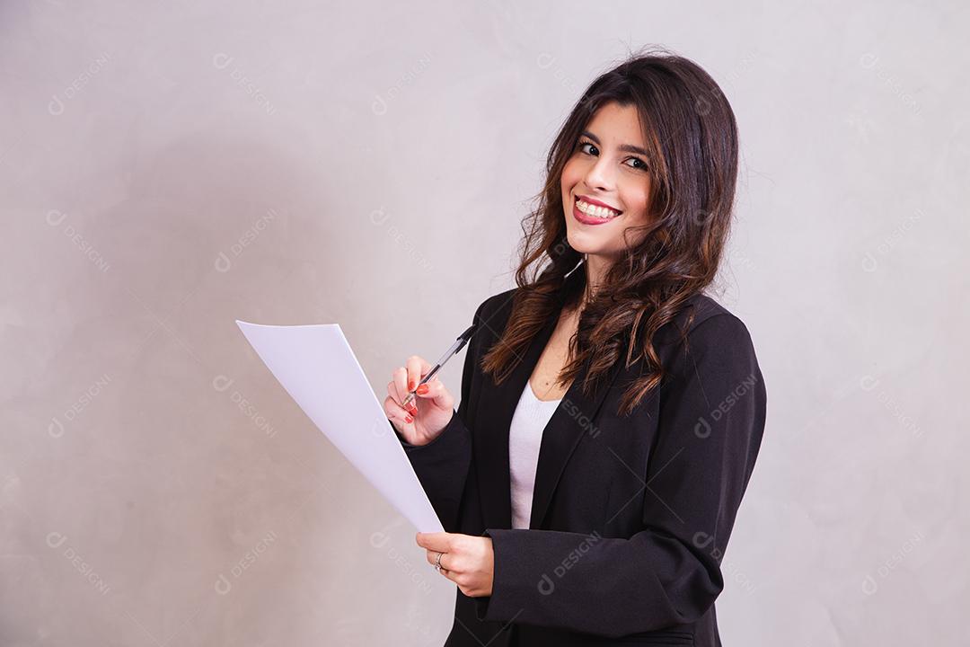 Mulher bonita de blazer preto segurando papel em fundo cinza