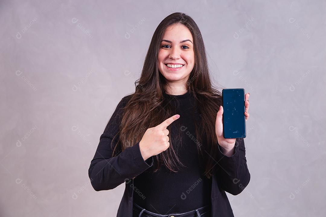 Mulher bonita de blazer preto Segurando celular em fundo cinza