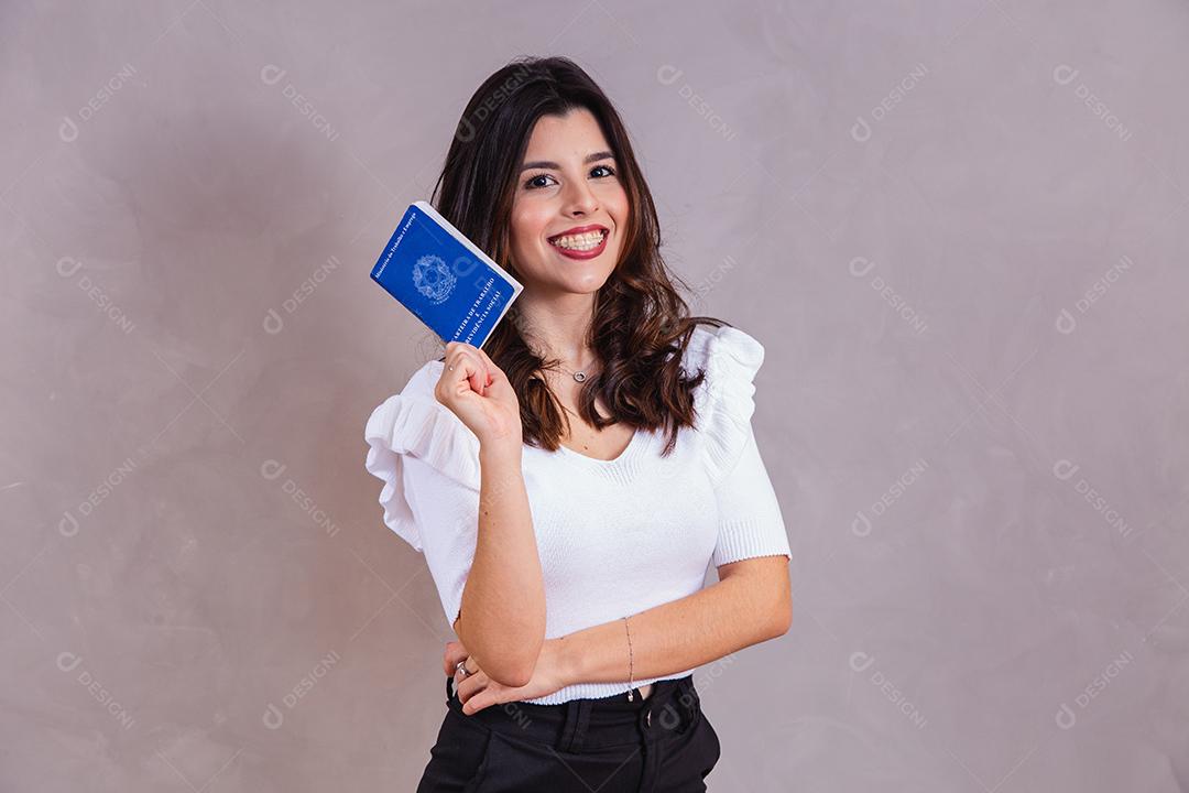 Mulher bonita com roupa branca segurando carteira de trabalho em fundo cinza