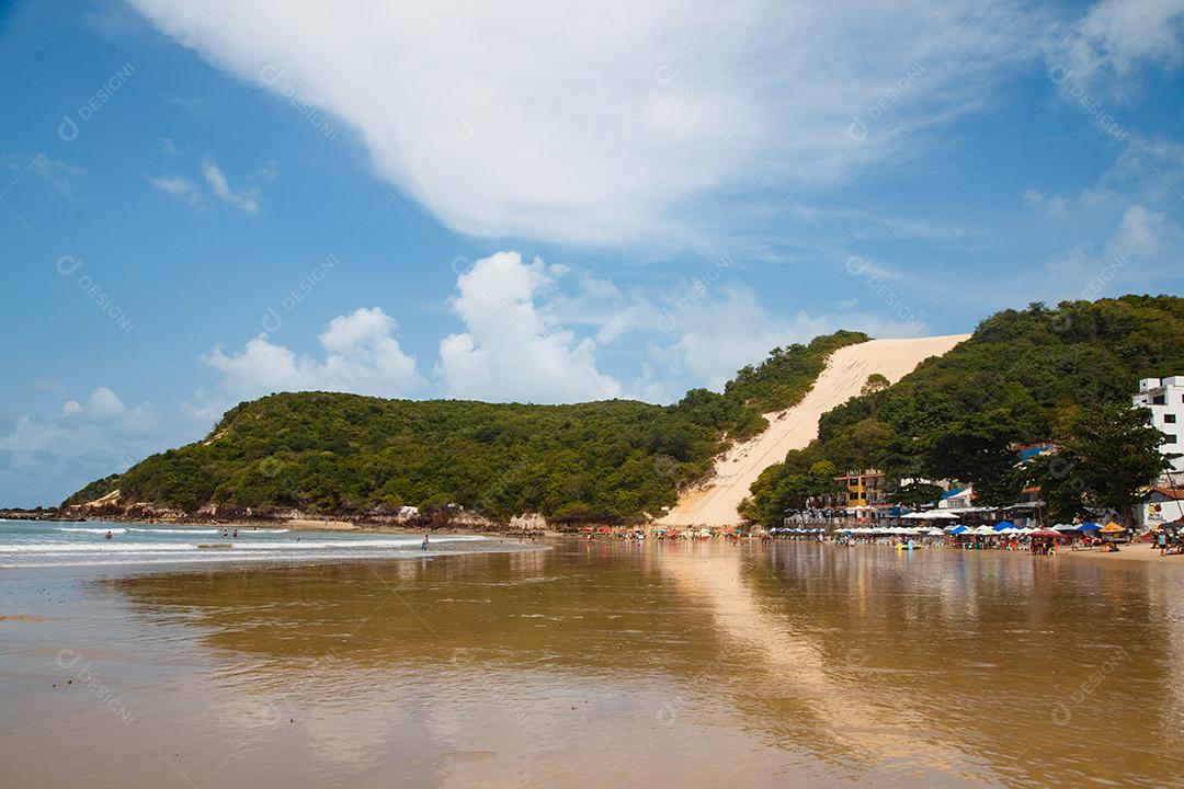 Montanha de areia com arvores beira mar com barcos em encosta