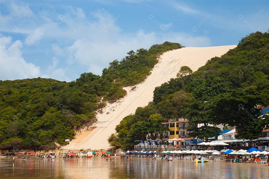 Montanha de areia com arvores beira mar com barcos em encosta