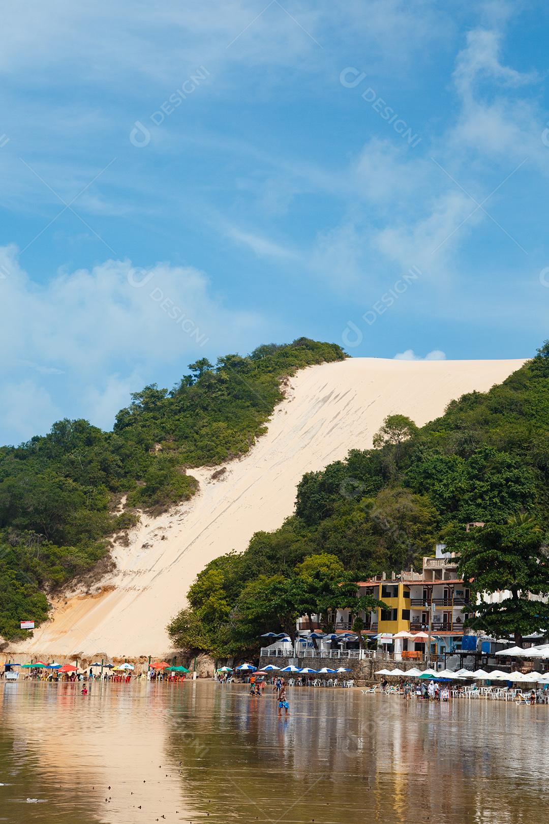 Montanha de areia com arvores beira mar com barcos em encosta