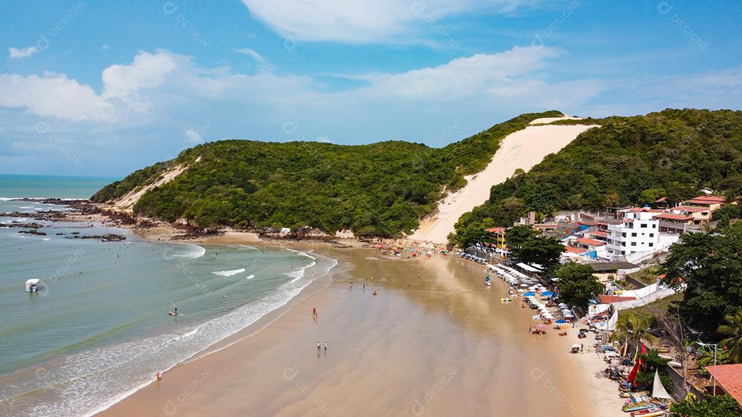 Montanha de areia com arvores beira mar com barcos em encosta