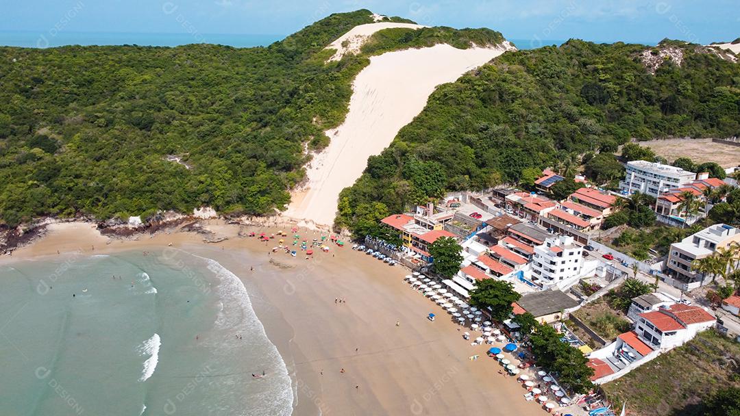 Montanha de areia com arvores beira mar com barcos em encosta