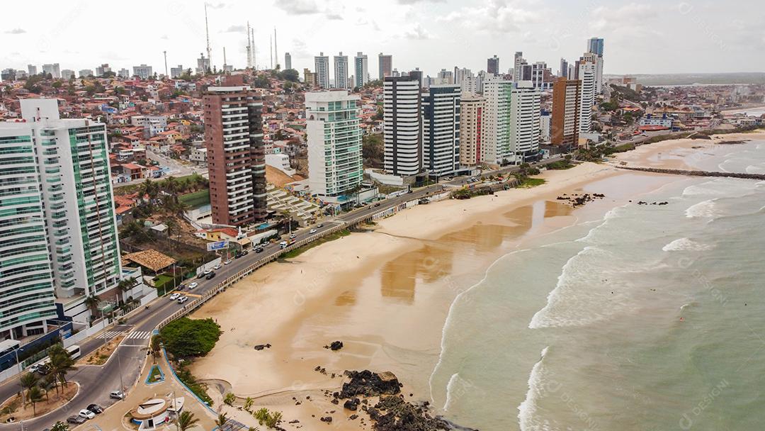 Praia em beira mar de cidade com varias prédios em dia ensolarado