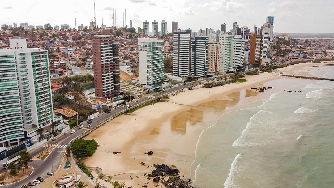 Praia em beira mar de cidade com varias prédios em dia ensolarado