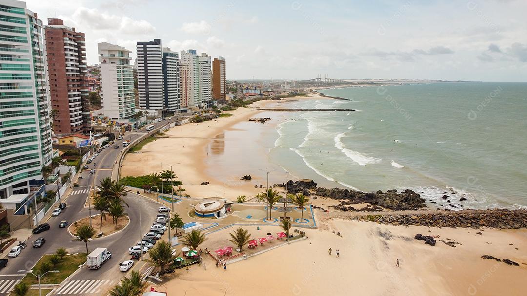 Praia em beira mar de cidade com varias prédios em dia ensolarado