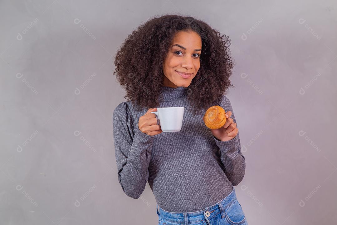 mulher afro comendo rosquinhas e tomando café