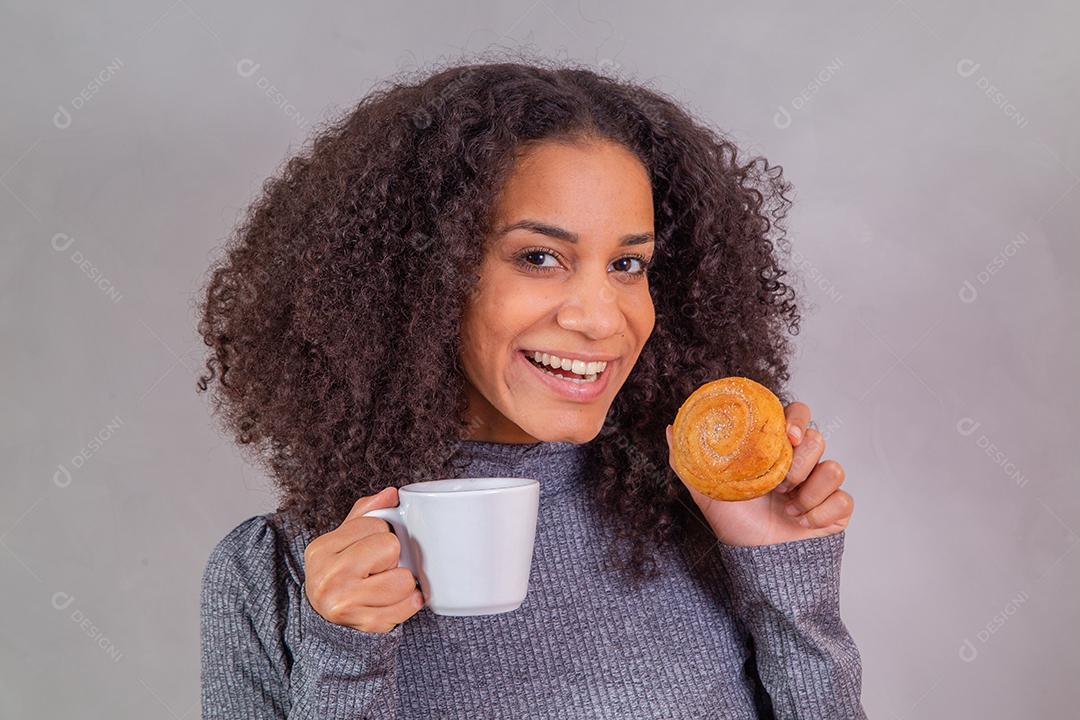 mulher afro comendo rosquinhas e tomando café