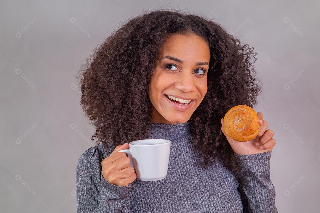 mulher afro comendo rosquinhas e tomando café