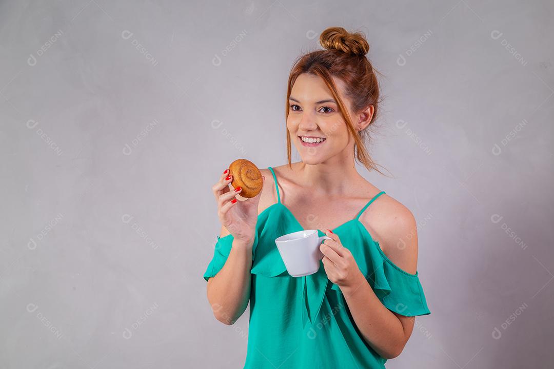 jovem ruiva comendo rosquinhas e bebendo chá no café da tarde