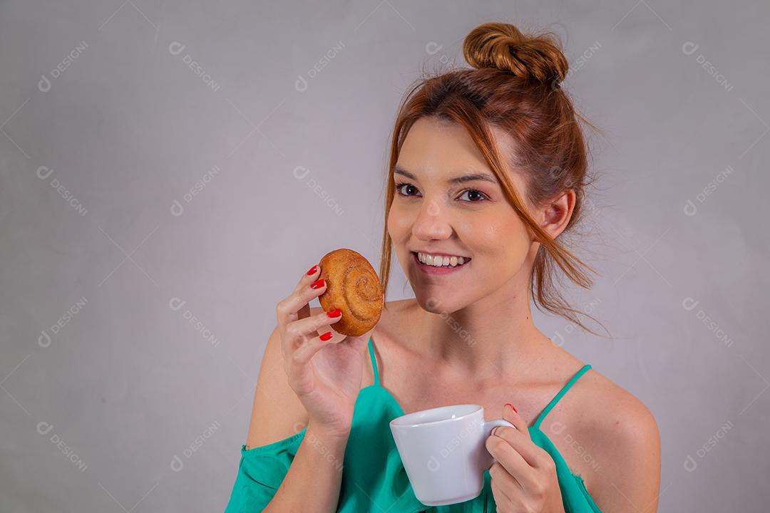 jovem ruiva comendo rosquinhas e bebendo chá no café da tarde