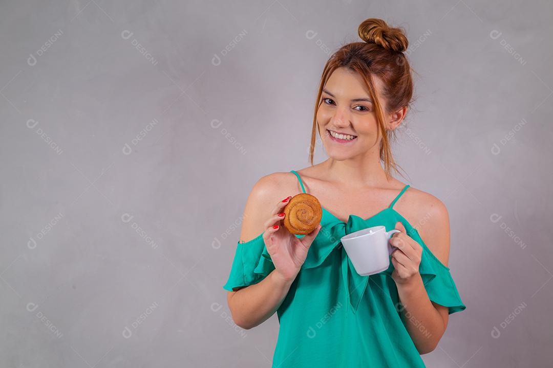 jovem ruiva comendo rosquinhas e bebendo chá no café da tarde