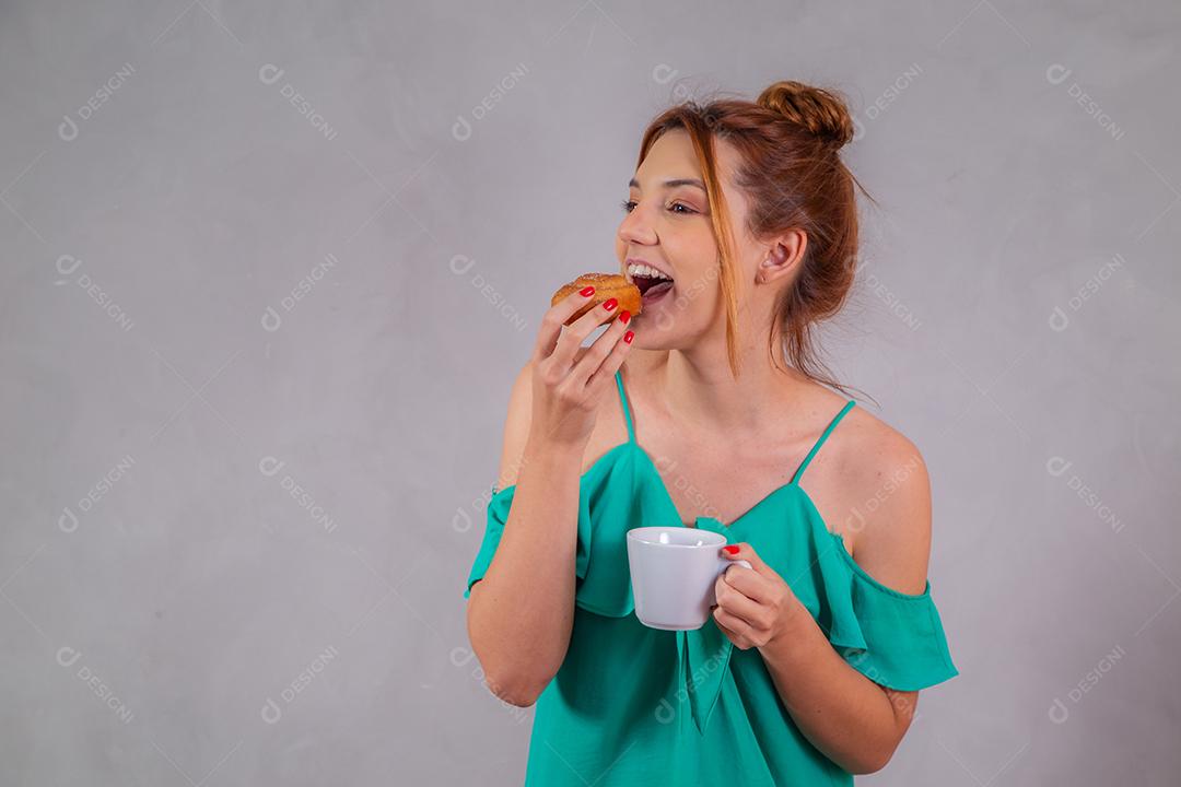 jovem ruiva comendo rosquinhas e bebendo chá no café da tarde