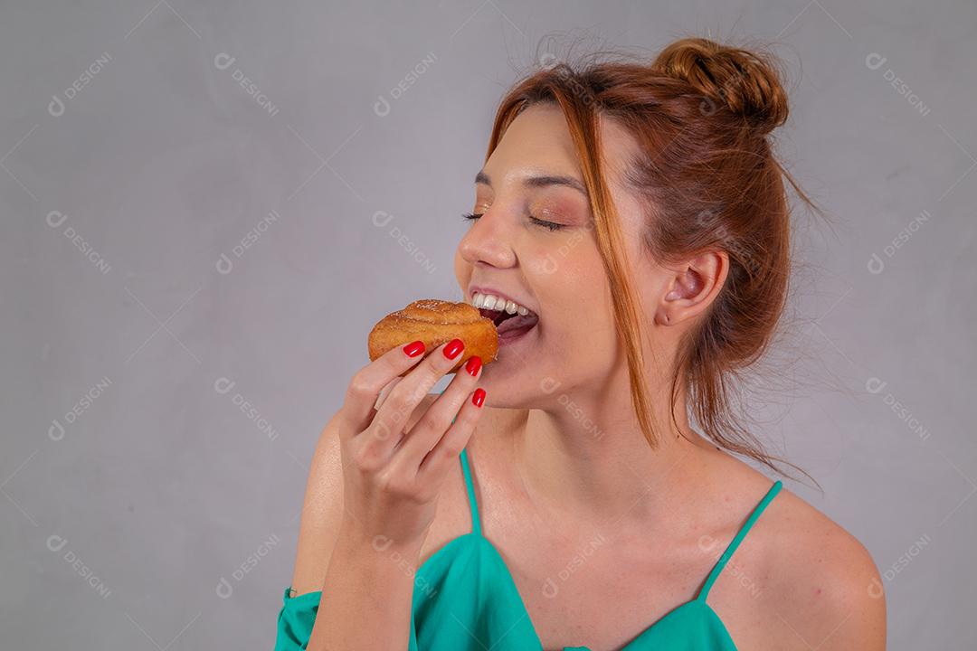 jovem ruiva comendo rosquinhas e bebendo chá no café da tarde